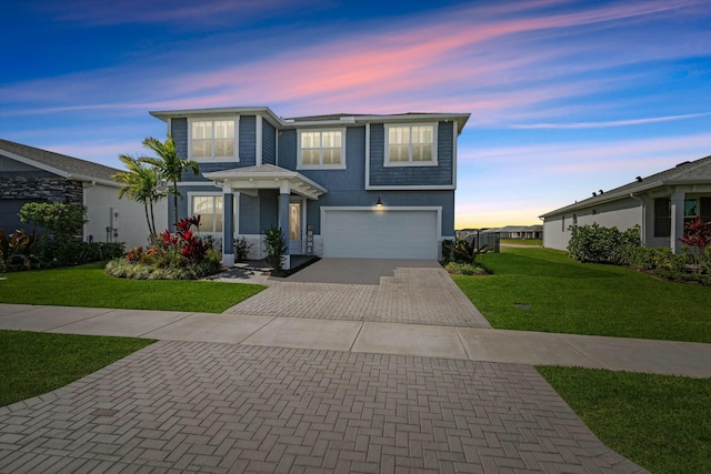 traditional-style house featuring an attached garage, decorative driveway, a lawn, and stucco siding