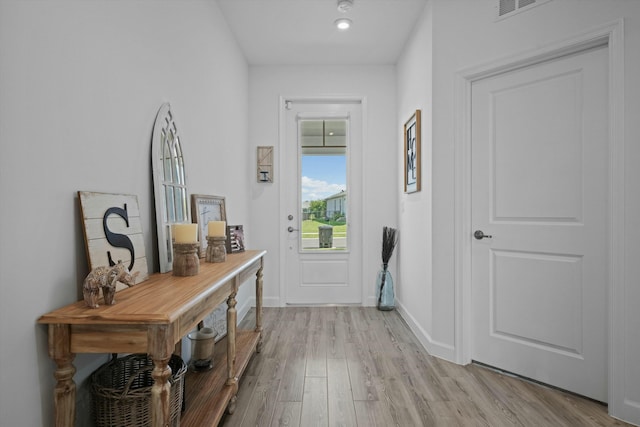 doorway featuring light wood finished floors, visible vents, and baseboards