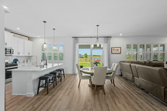 dining room featuring an inviting chandelier, light wood-style flooring, baseboards, and recessed lighting