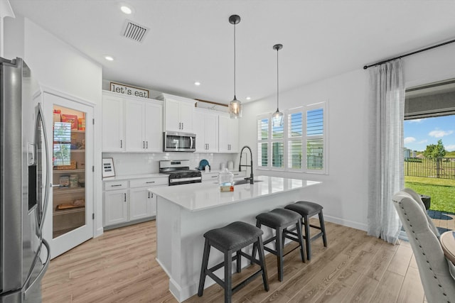 kitchen with light wood finished floors, tasteful backsplash, visible vents, appliances with stainless steel finishes, and a sink