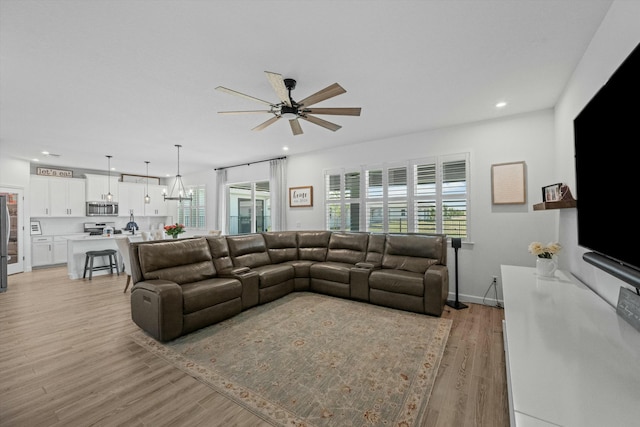 living area featuring plenty of natural light, ceiling fan with notable chandelier, light wood-type flooring, and recessed lighting