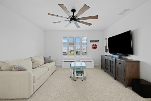 living room with baseboards, visible vents, a ceiling fan, and light colored carpet