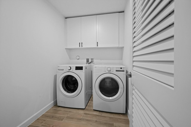 clothes washing area featuring washer and dryer, cabinet space, baseboards, and wood tiled floor