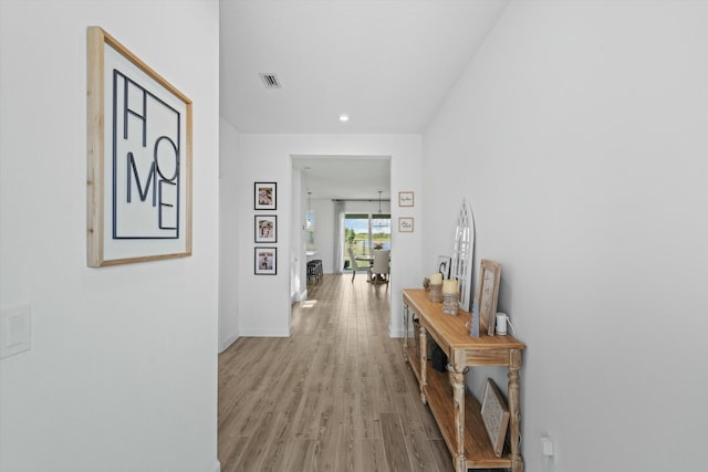 hall featuring light wood finished floors, visible vents, and baseboards