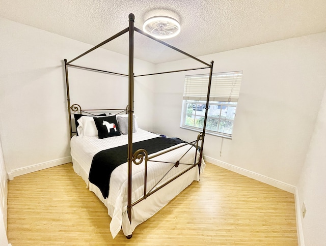 bedroom featuring baseboards, a textured ceiling, and light wood-style flooring