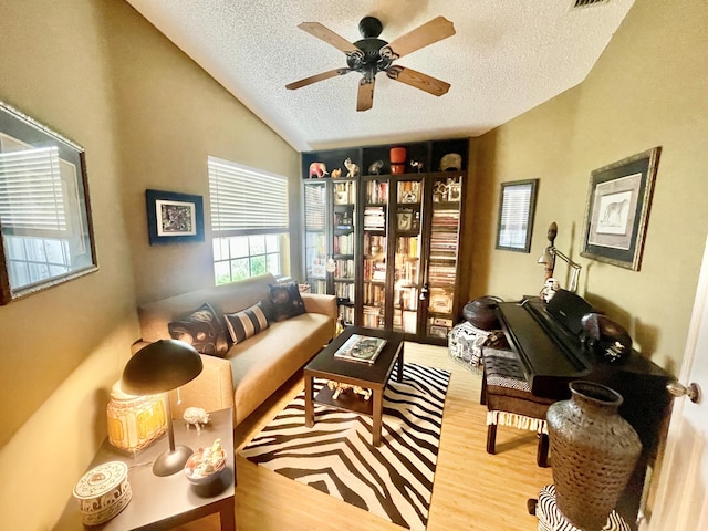 sitting room with a textured ceiling, wood finished floors, a ceiling fan, and vaulted ceiling