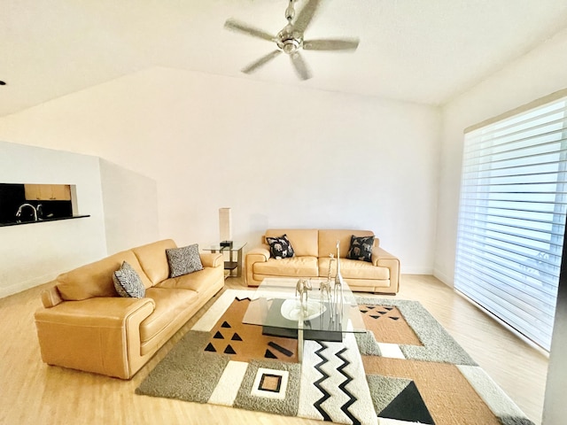 living room featuring vaulted ceiling, wood finished floors, baseboards, and ceiling fan