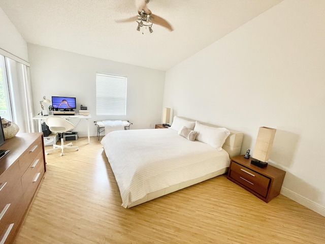 bedroom featuring baseboards, light wood-type flooring, a ceiling fan, and vaulted ceiling