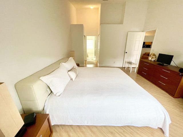 bedroom featuring light wood-style floors and a high ceiling