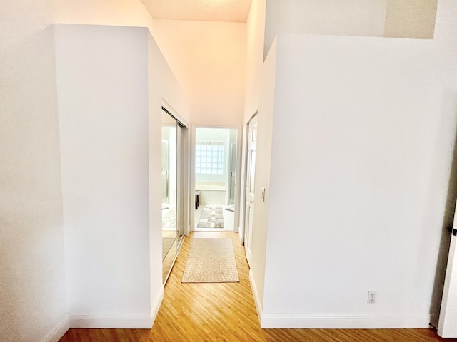 corridor with baseboards and light wood-style flooring