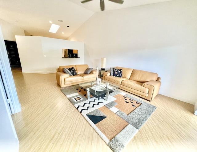 living area with ceiling fan, high vaulted ceiling, wood finished floors, and a skylight