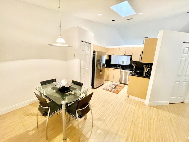 dining space featuring baseboards, light wood finished floors, high vaulted ceiling, a skylight, and recessed lighting