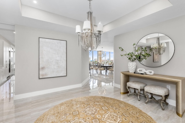 corridor featuring a tray ceiling, a notable chandelier, baseboards, and recessed lighting