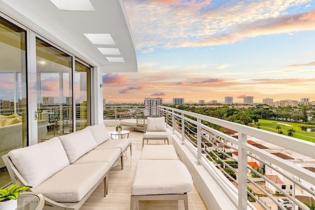 balcony at dusk featuring an outdoor hangout area and a city view