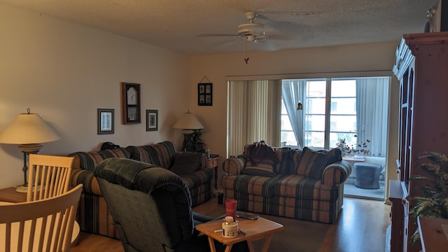 living room featuring ceiling fan, a textured ceiling, and wood finished floors