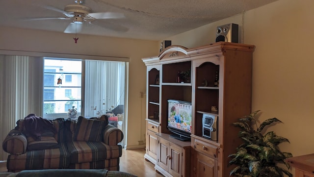 living area featuring light wood-style floors, ceiling fan, and a textured ceiling