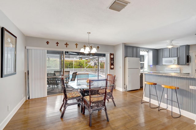 dining space with baseboards, visible vents, and light wood-style floors