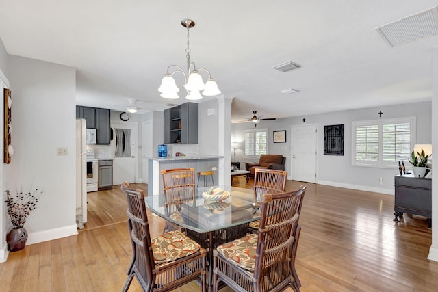 dining room featuring ceiling fan with notable chandelier, light wood-type flooring, visible vents, and a healthy amount of sunlight