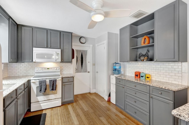 kitchen with light wood-style flooring, white appliances, gray cabinets, light stone countertops, and open shelves