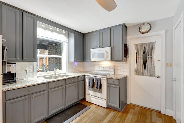 kitchen with gray cabinets, light wood-type flooring, white appliances, and a sink