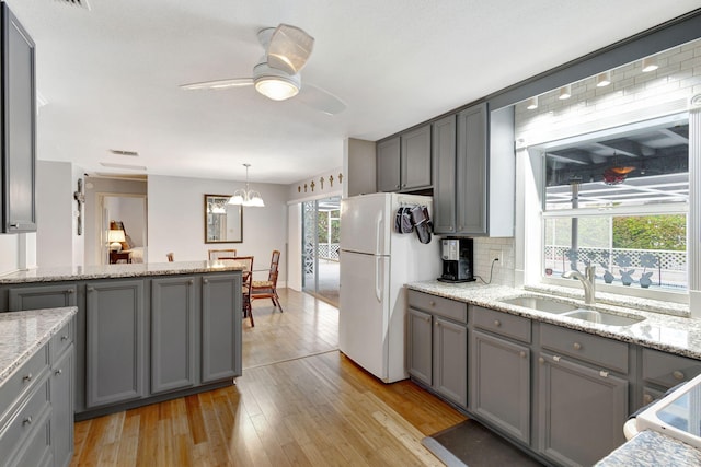 kitchen featuring white appliances, gray cabinets, a sink, and decorative light fixtures