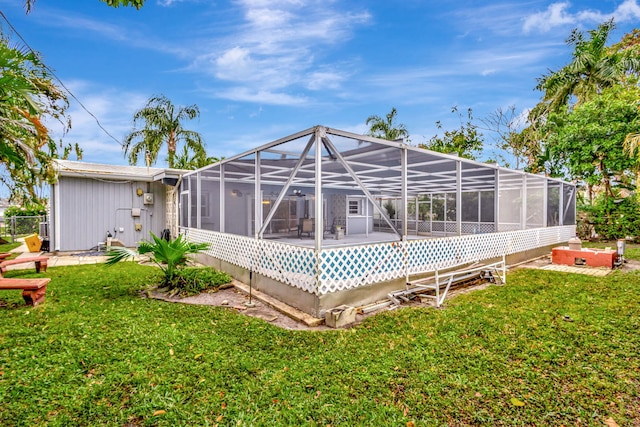 back of house with a lanai, a yard, and a hot tub