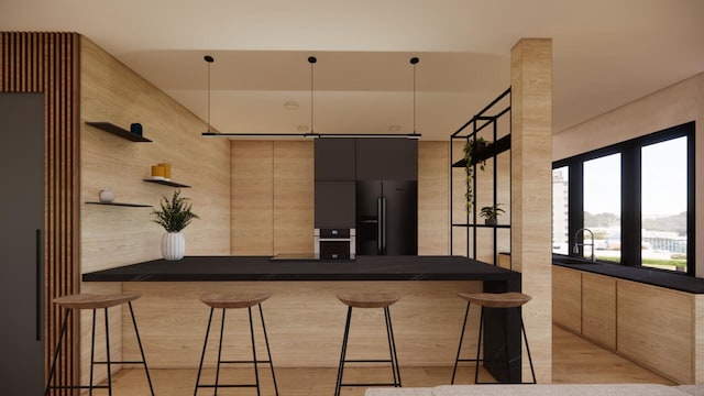 kitchen with a breakfast bar, open shelves, a sink, dark countertops, and black fridge