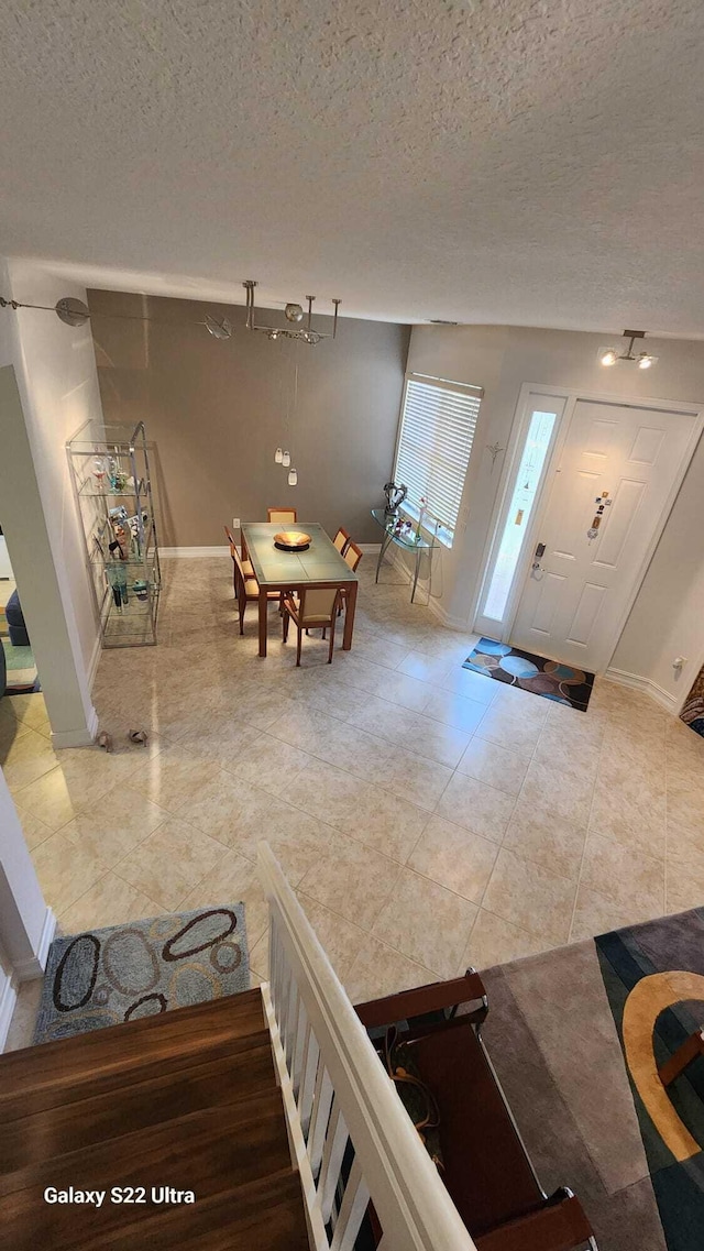 foyer entrance with baseboards, a textured ceiling, and tile patterned floors