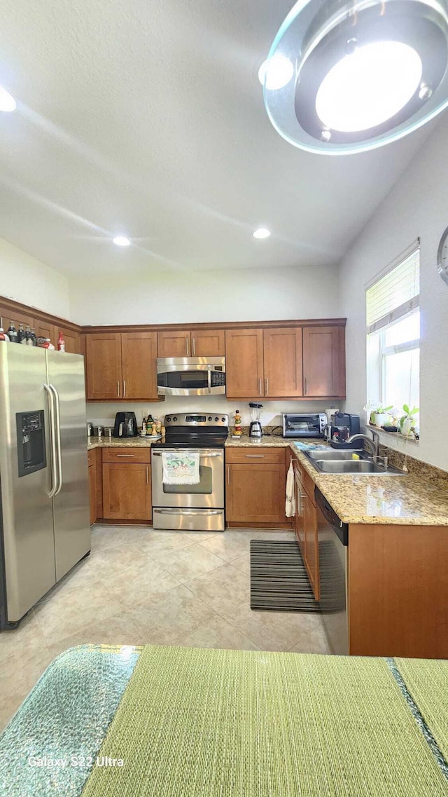 kitchen with a toaster, recessed lighting, appliances with stainless steel finishes, brown cabinetry, and a sink