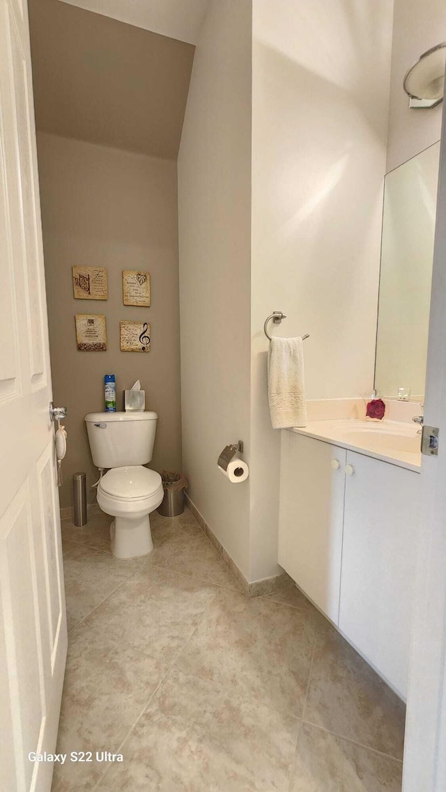 half bath with toilet, tile patterned flooring, baseboards, and vanity