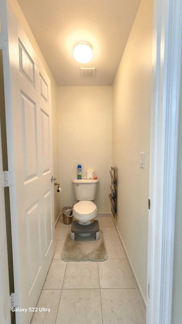 bathroom featuring baseboards, visible vents, toilet, and tile patterned floors