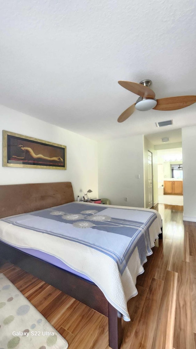 bedroom featuring a ceiling fan, visible vents, and wood finished floors