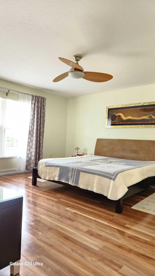 bedroom featuring a textured ceiling, wood finished floors, and a ceiling fan