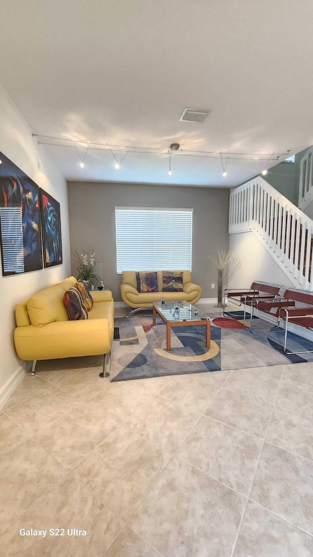 tiled living area with visible vents, track lighting, stairway, and baseboards