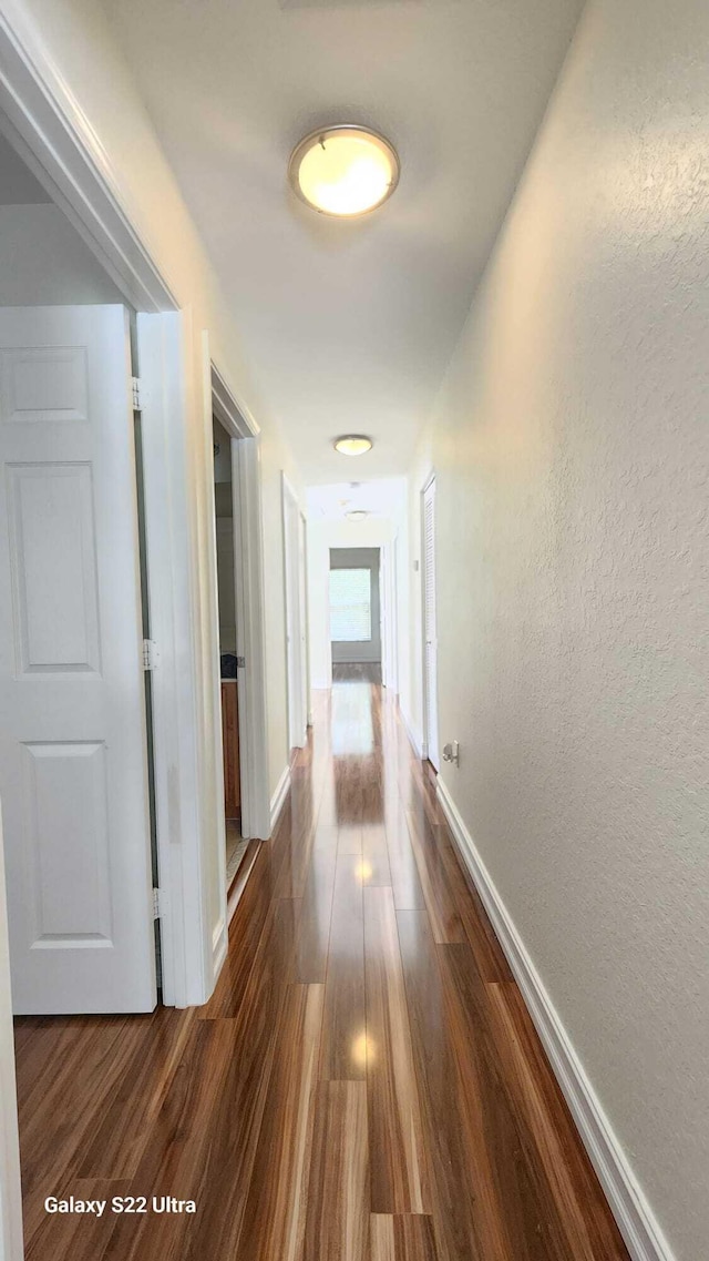 hall with baseboards, dark wood-style flooring, and a textured wall