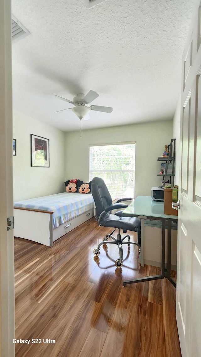 bedroom featuring a textured ceiling, ceiling fan, and wood finished floors