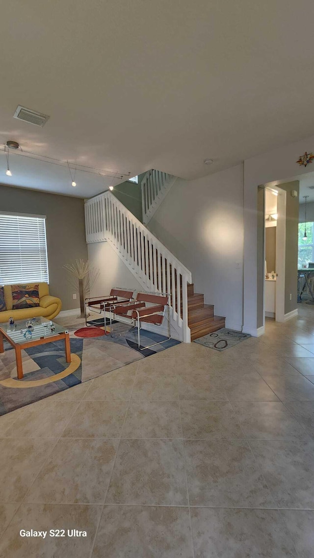 living room featuring visible vents, stairway, baseboards, and light tile patterned floors