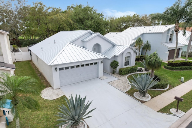 view of front of property featuring metal roof, an attached garage, a gate, stucco siding, and a standing seam roof