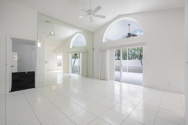 spare room with ceiling fan, high vaulted ceiling, a textured ceiling, and tile patterned floors