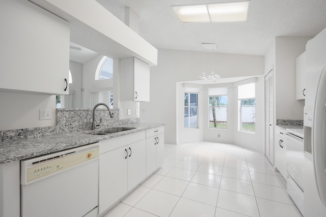 kitchen with light tile patterned floors, white dishwasher, vaulted ceiling, white cabinetry, and a sink