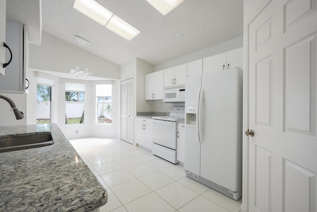 kitchen with light tile patterned floors, white cabinetry, vaulted ceiling, a sink, and white appliances