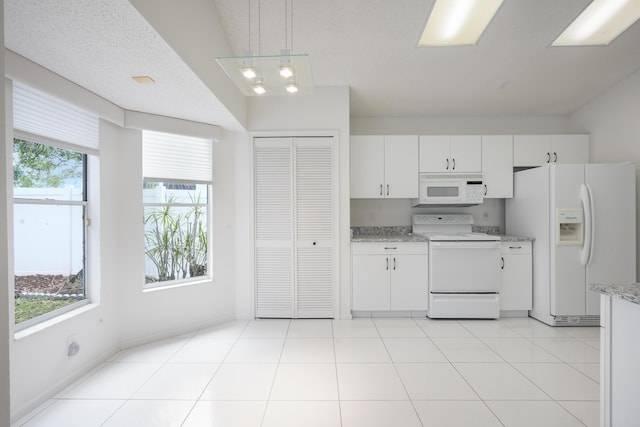 kitchen featuring white appliances, light tile patterned flooring, decorative light fixtures, and white cabinets