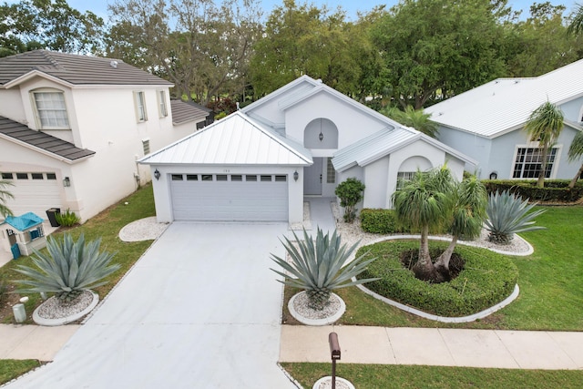 view of front of property featuring stucco siding, an attached garage, a front yard, metal roof, and driveway