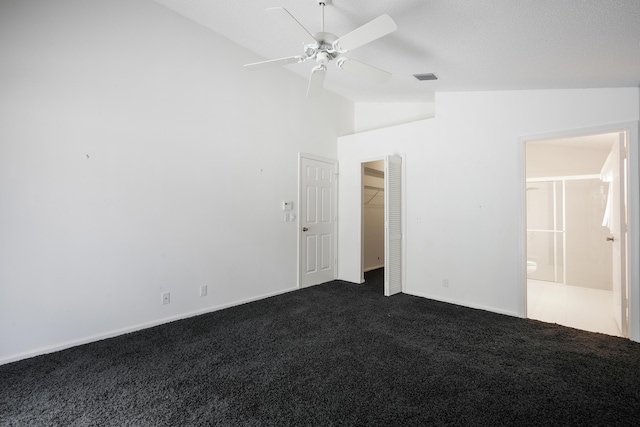 unfurnished bedroom with lofted ceiling, ceiling fan, dark carpet, and visible vents