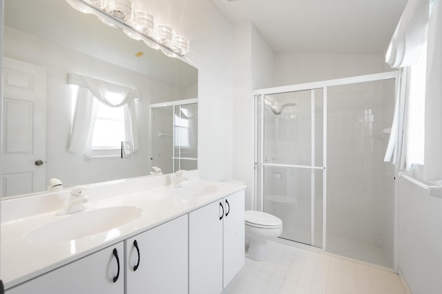 bathroom featuring toilet, a stall shower, double vanity, and a sink