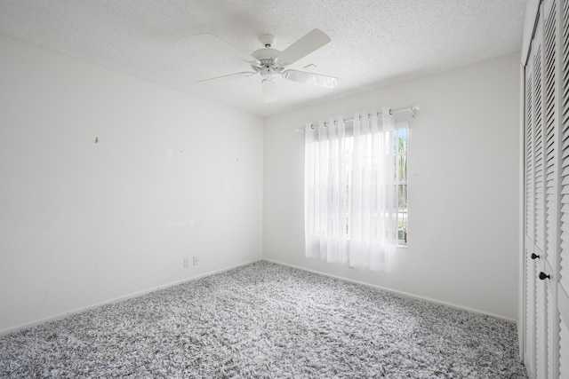 empty room with a ceiling fan, carpet flooring, a textured ceiling, and baseboards