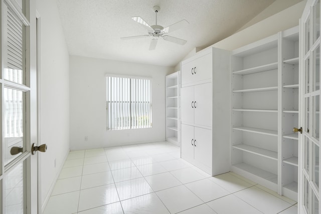 spare room featuring light tile patterned floors, a ceiling fan, vaulted ceiling, a textured ceiling, and french doors