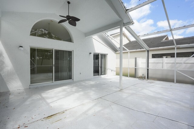 unfurnished sunroom with a ceiling fan and vaulted ceiling