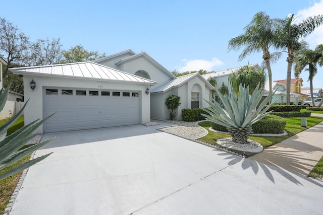 view of front facade featuring stucco siding, concrete driveway, an attached garage, a standing seam roof, and metal roof