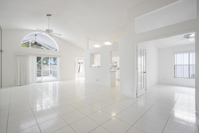 unfurnished living room with high vaulted ceiling, light tile patterned floors, visible vents, and a ceiling fan